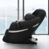 Positive Posture Brio+ massage chair in Black by a large window with an ocean view.