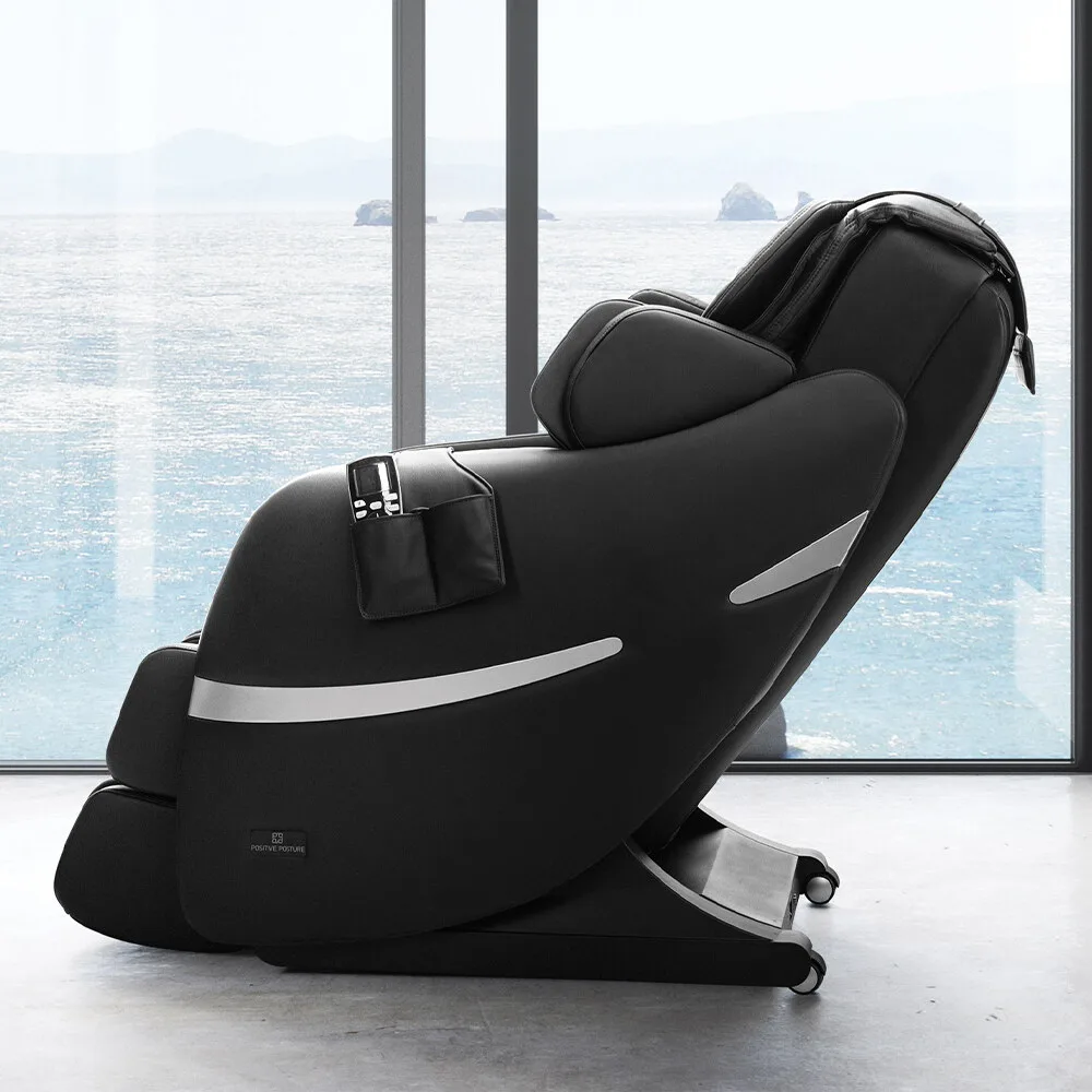 Positive Posture Brio+ massage chair in Black by a large window with an ocean view.