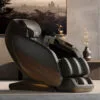 Positive Posture DualTech Pro AI 4D massage chair in Charcoal in a living room with a city view.
